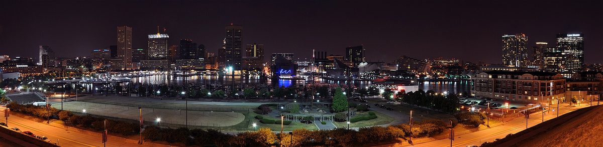 Baltimore Inner Harbor skyline at night with city lights reflecting on the water.